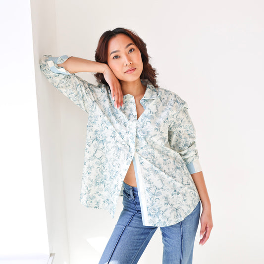 Woman wearing a floral shirt and jeans against a white background