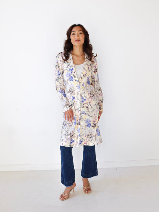 Woman wearing a floral coat and blue jeans against a white background