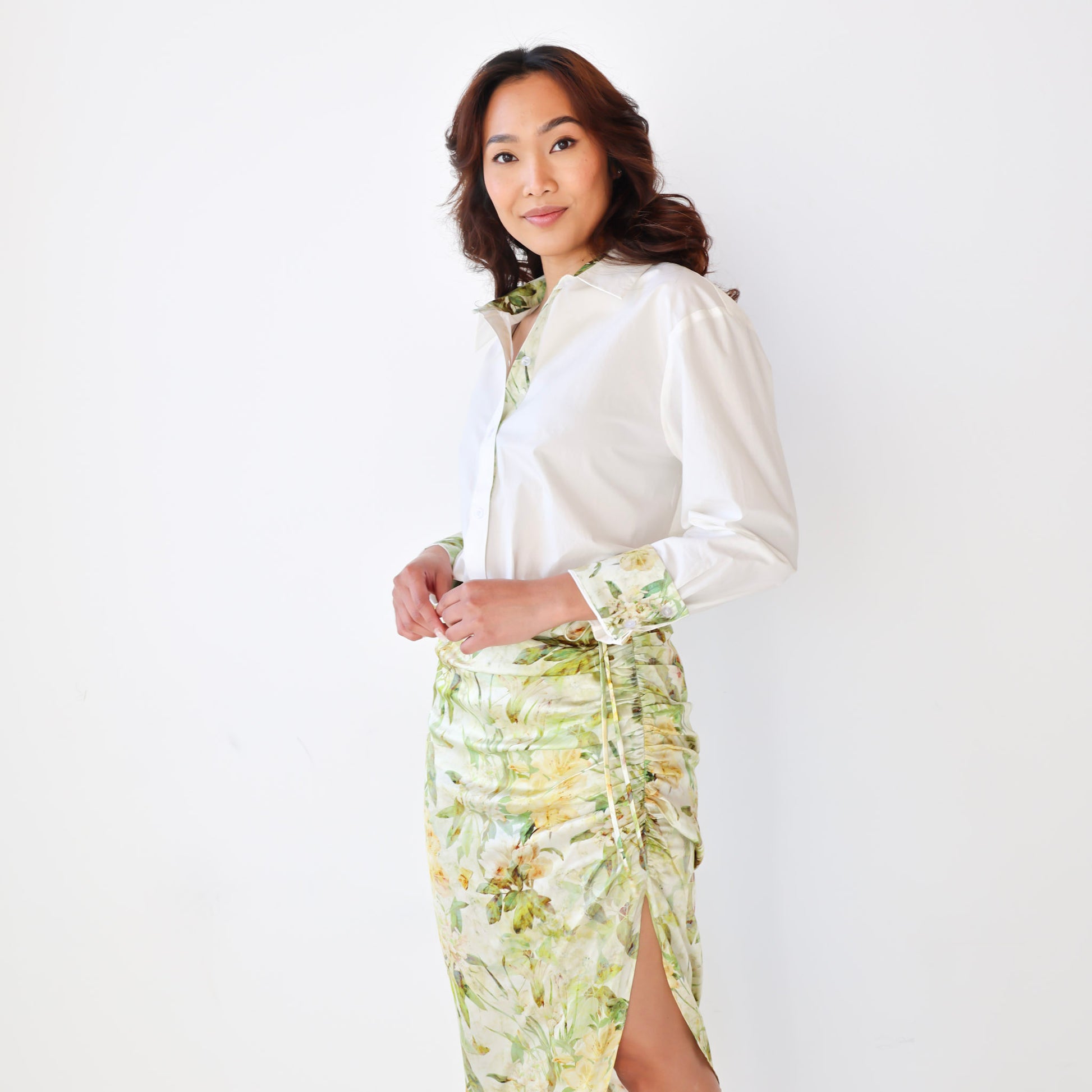 Woman wearing a white blouse and floral skirt against a white background