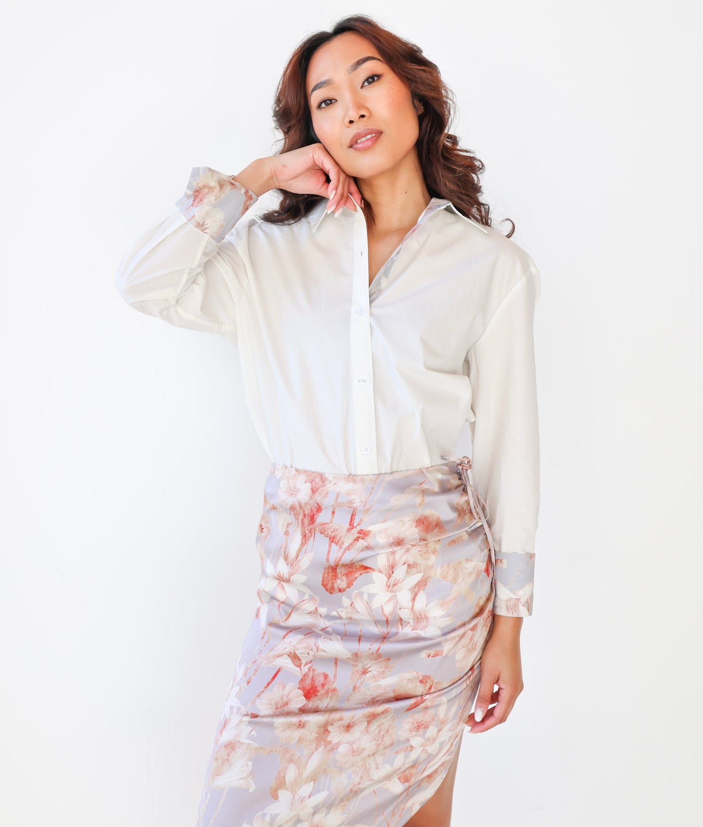 Woman wearing a white blouse and floral skirt on a white background